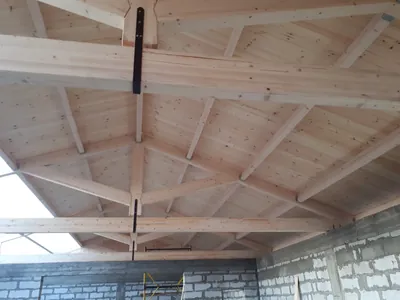 Tavanul unui acoperiș din lemn lamelar cu grindă centrală și soffit alb, deasupra unei încăperi ample — LEMNER.MD
