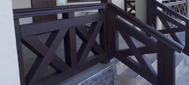 Scară exterioară cu balustradă din lemn vopsit închis în X, pe trepte placate cu piatră — LEMNER.MD