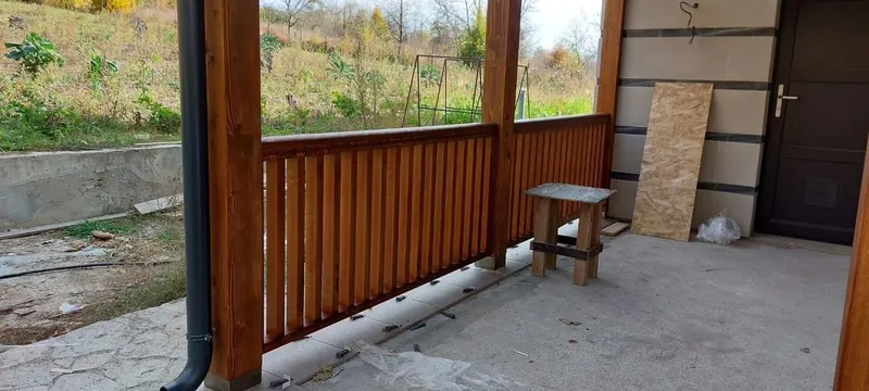 Terasă acoperită din lemn cu balustradă verticală și stâlpi, lângă casă, cu vedere spre grădină — LEMNER.MD