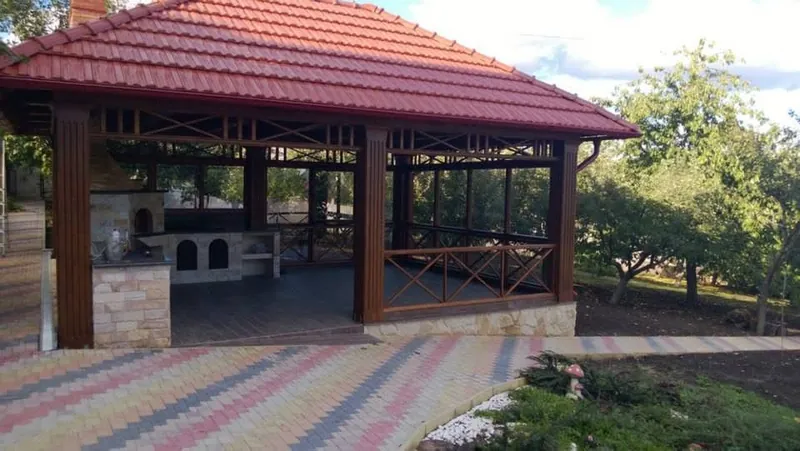 Foișor mare din lemn cu acoperiș în patru ape din țiglă roșie și zonă de grătar din cărămidă, pe alee pavată colorată — LEMNER.MD