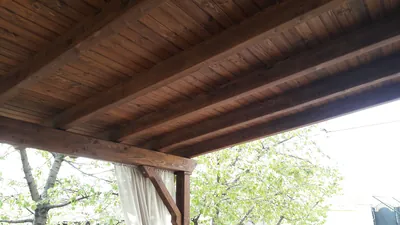 Tavanul din scânduri și grinzi de lemn al unei terase acoperite, vedere de jos — LEMNER.MD