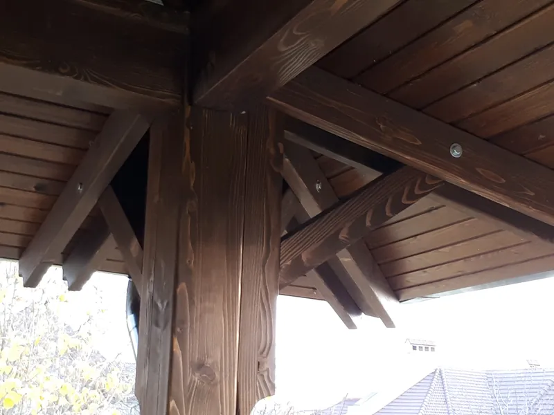 Detaliu de îmbinare a grinzilor de lemn la colțul unui foișor, vedere de jos — LEMNER.MD