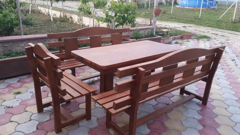 Set de masă cu două bănci din lemn vopsit în nuanță roșcată, pe pavaj, în curte — LEMNER.MD