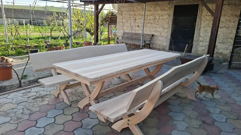Set de masă cu bănci din lemn deschis la culoare, pe o terasă pavată, lângă casă — LEMNER.MD