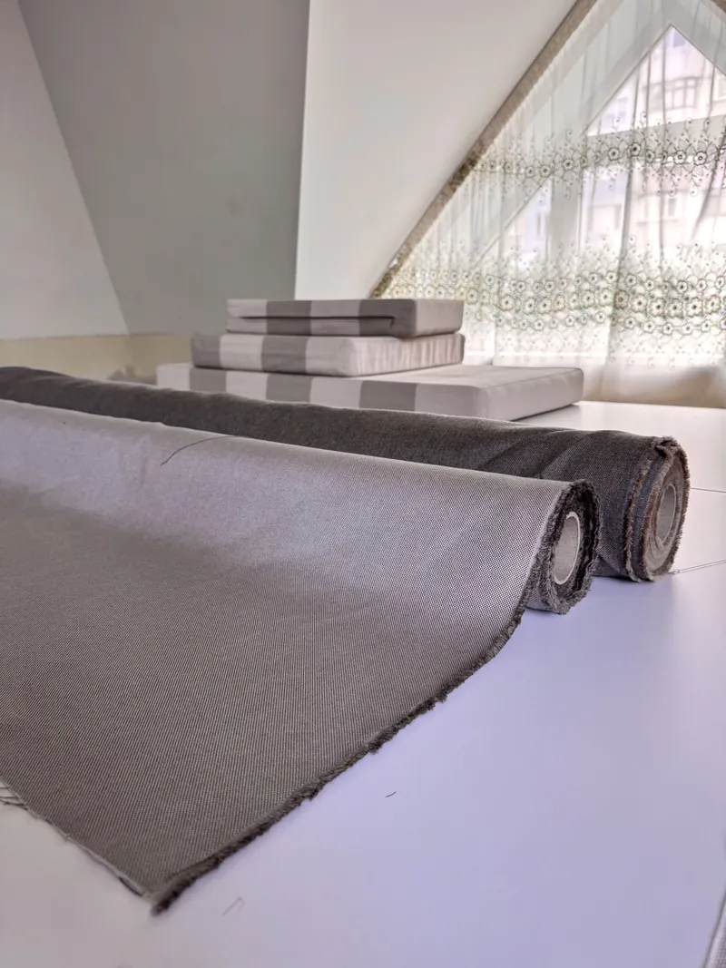 Țesături și perne pentru mobilierul de terasă — rulou de material gri și perne în dungi, lângă fereastră — LEMNER.MD