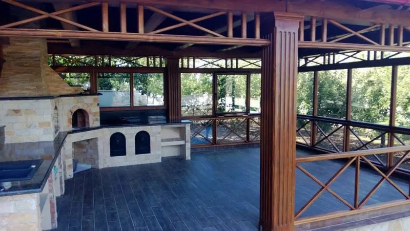 Terasă acoperită din lemn cu zonă de grătar și cuptor din piatră, stâlpi canelați și balustradă în X — LEMNER.MD